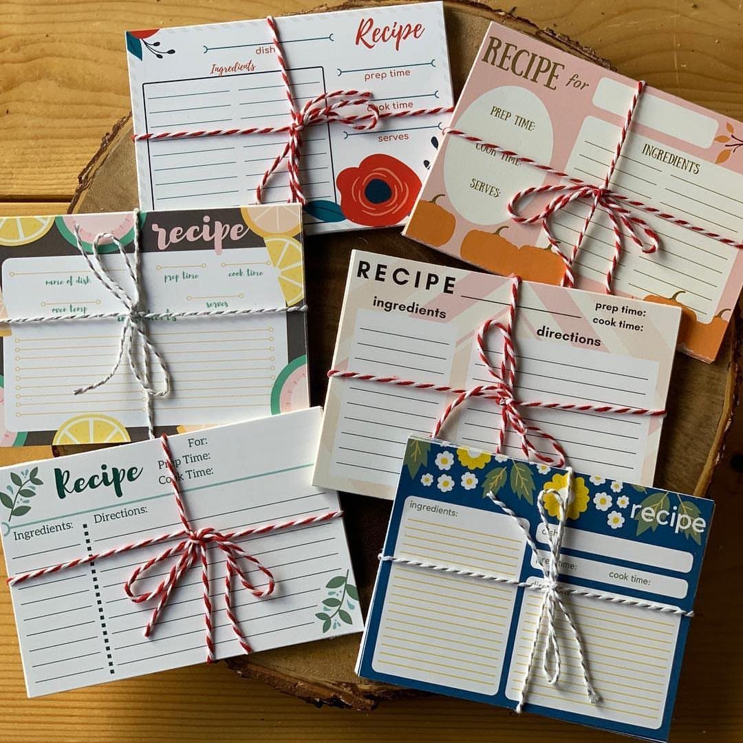 Bundles of colorful printed recipe cards tied with twine on a wooden platter