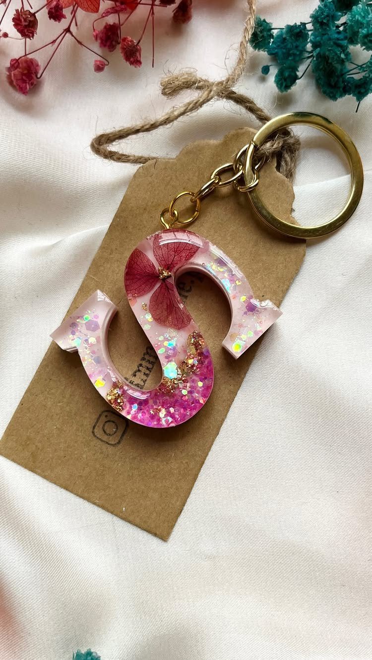 Resin letter S keychain with pink glitter and dried flower on cardboard tag