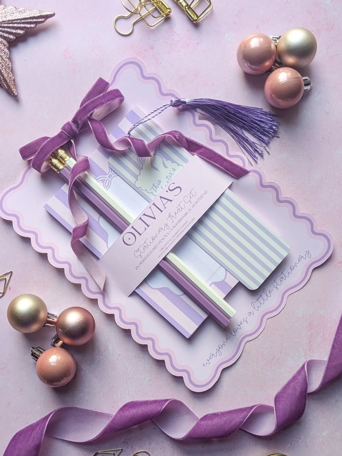 Personalized purple stationery set with notebooks and pencils tied with a purple ribbon.
