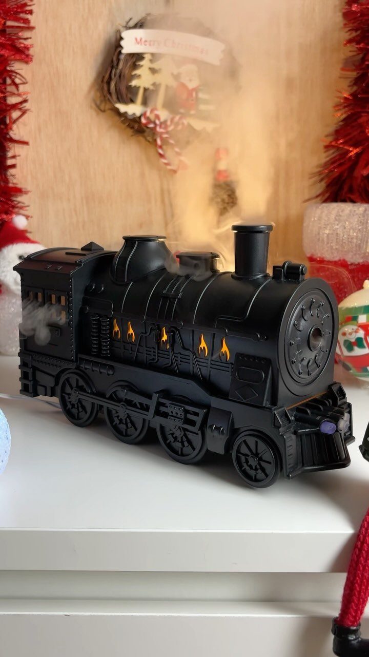 14 Holiday Christmas Gifts for Kids, Couples and Coworkers 13 Black toy steam locomotive with glowing lights on a white surface near Christmas decorations