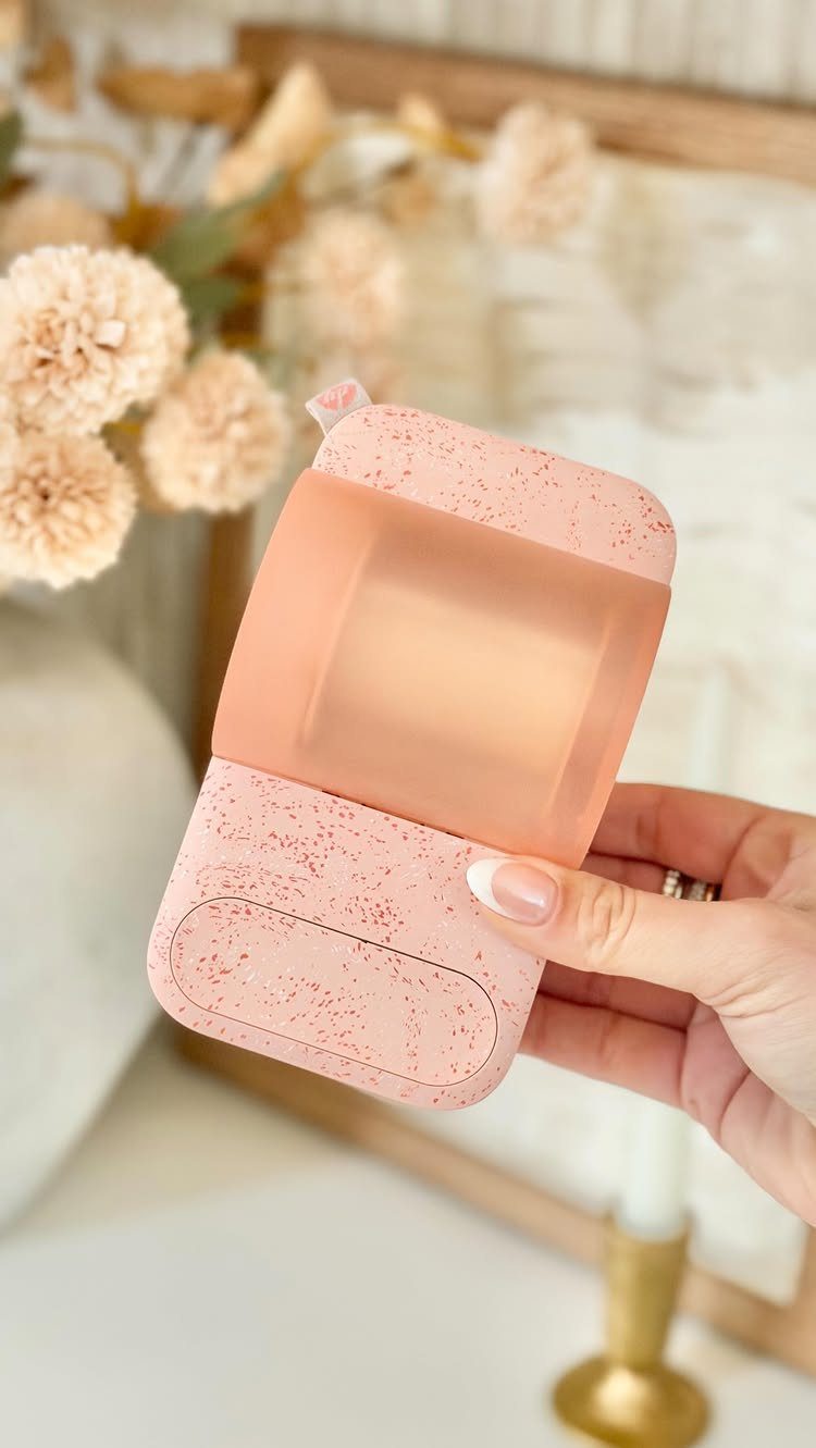 14 Holiday Christmas Gifts for Kids, Couples and Coworkers 14 Pink speckled earbud case held by a hand against a floral background