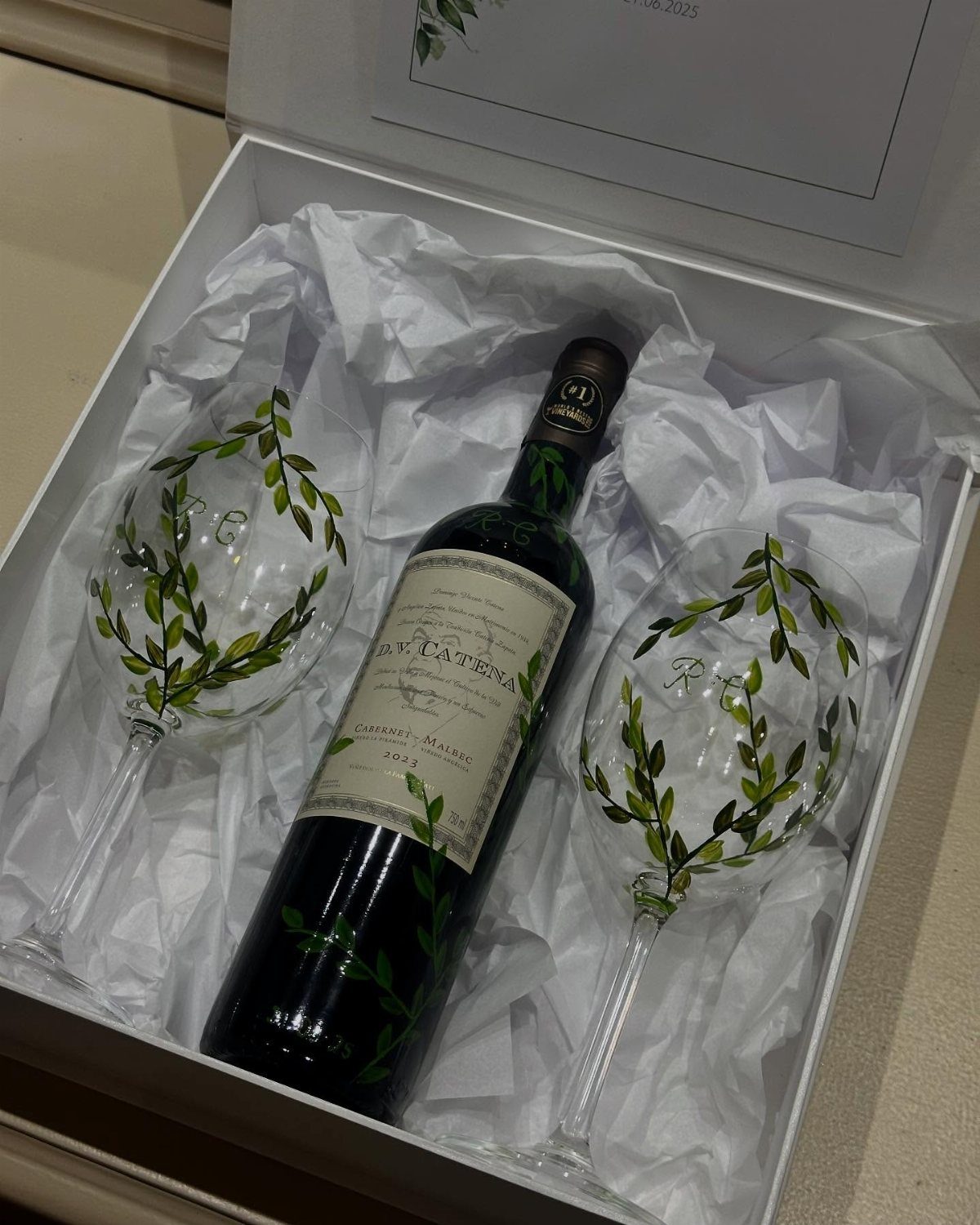 Wine bottle and two personalized wine glasses with leaf designs in a white box