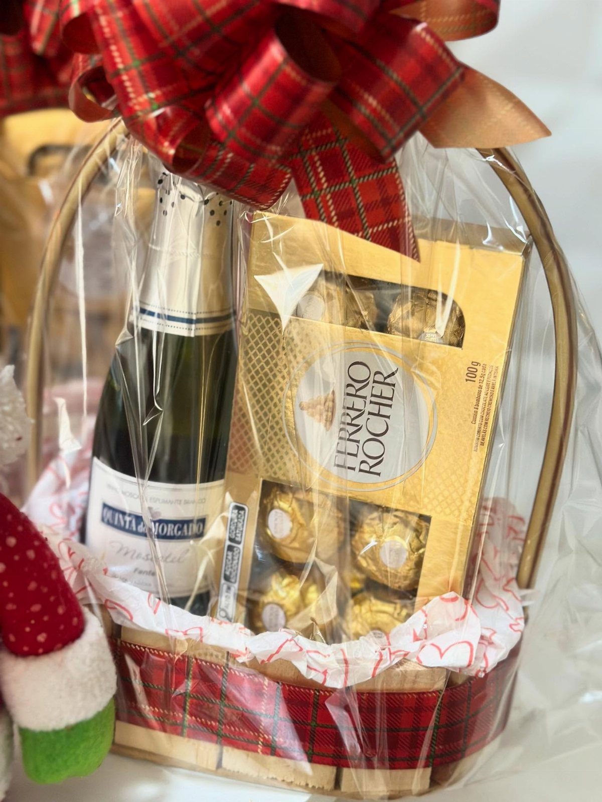 Holiday gift basket with sparkling wine and Ferrero Rocher chocolates wrapped in cellophane.