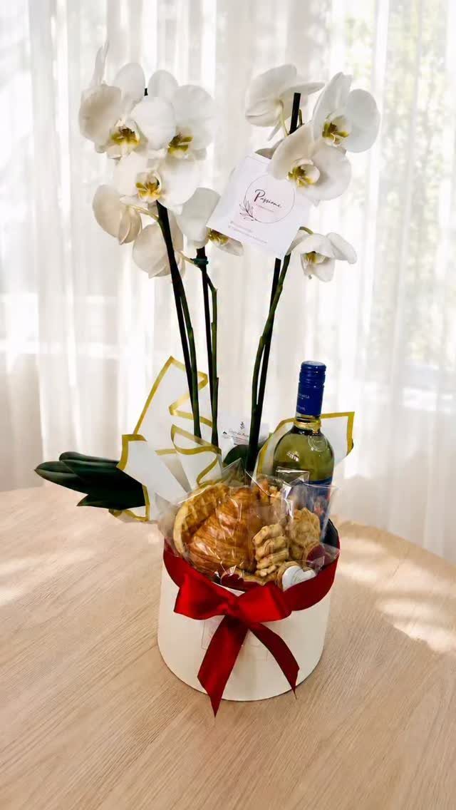 White orchid plant and wine bottle in a gift box with red ribbon