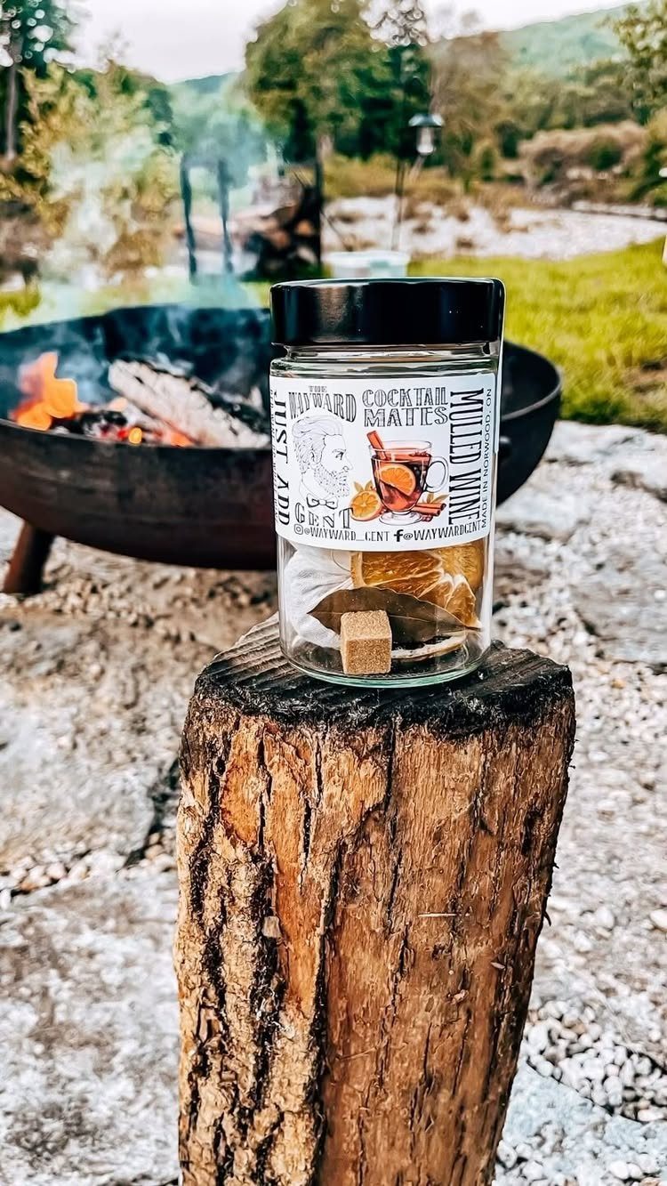 Holiday Wine Gift Ideas: 6 Baskets, Sets, and Sparkling Picks 6 Mulled wine kit jar with spices on a wooden stump near a fire pit.