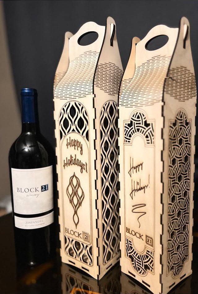 Holiday Wine Gift Ideas: 6 Baskets, Sets, and Sparkling Picks 3 Red wine bottle and two engraved wooden wine carriers with holiday greetings.
