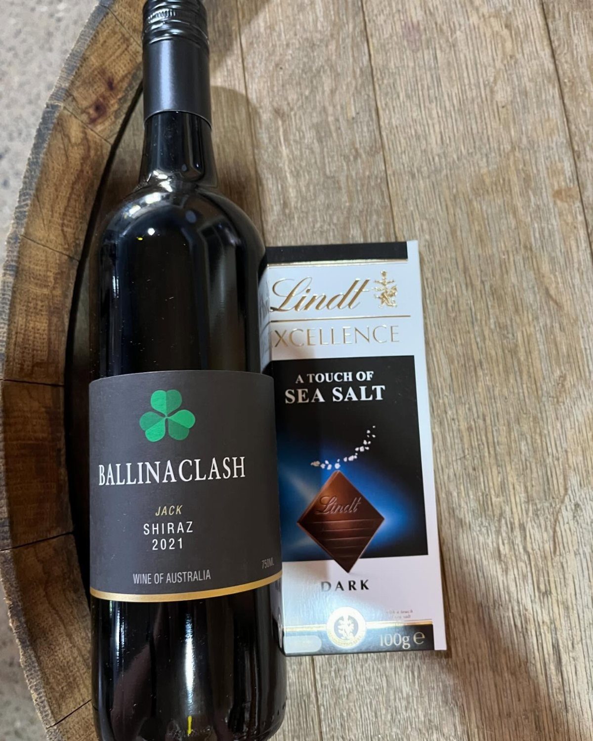 Holiday Wine Gift Ideas: 6 Baskets, Sets, and Sparkling Picks 4 Bottle of red wine and a dark chocolate bar on a wooden barrel.