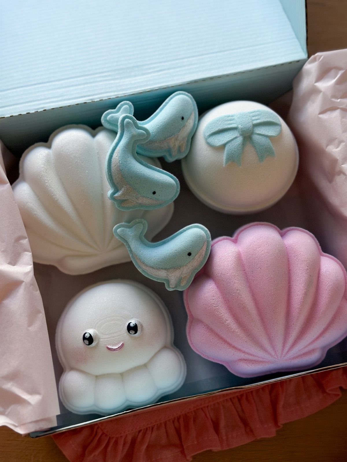 Ocean-themed bath bombs in a blue box, including seashells, whales, and an octopus.