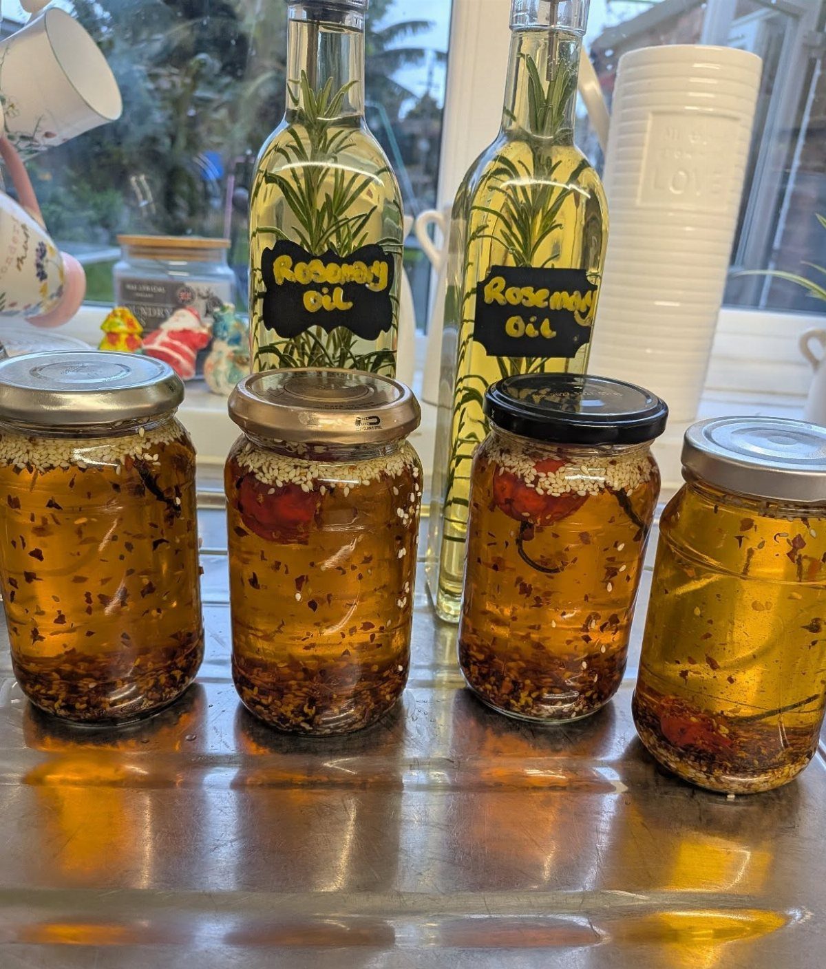 Infused oils in glass jars and bottles with rosemary and chili herbs.