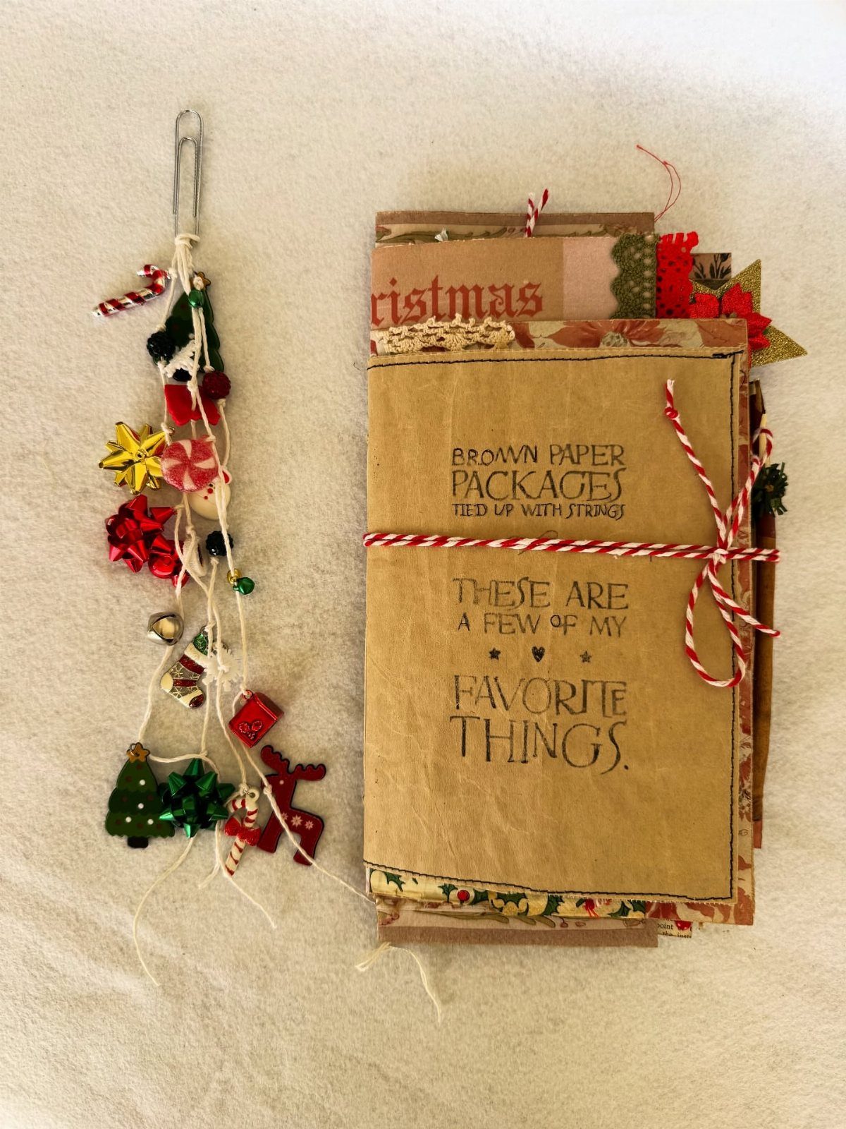 Handmade brown paper journal tied with red twine next to Christmas charms.