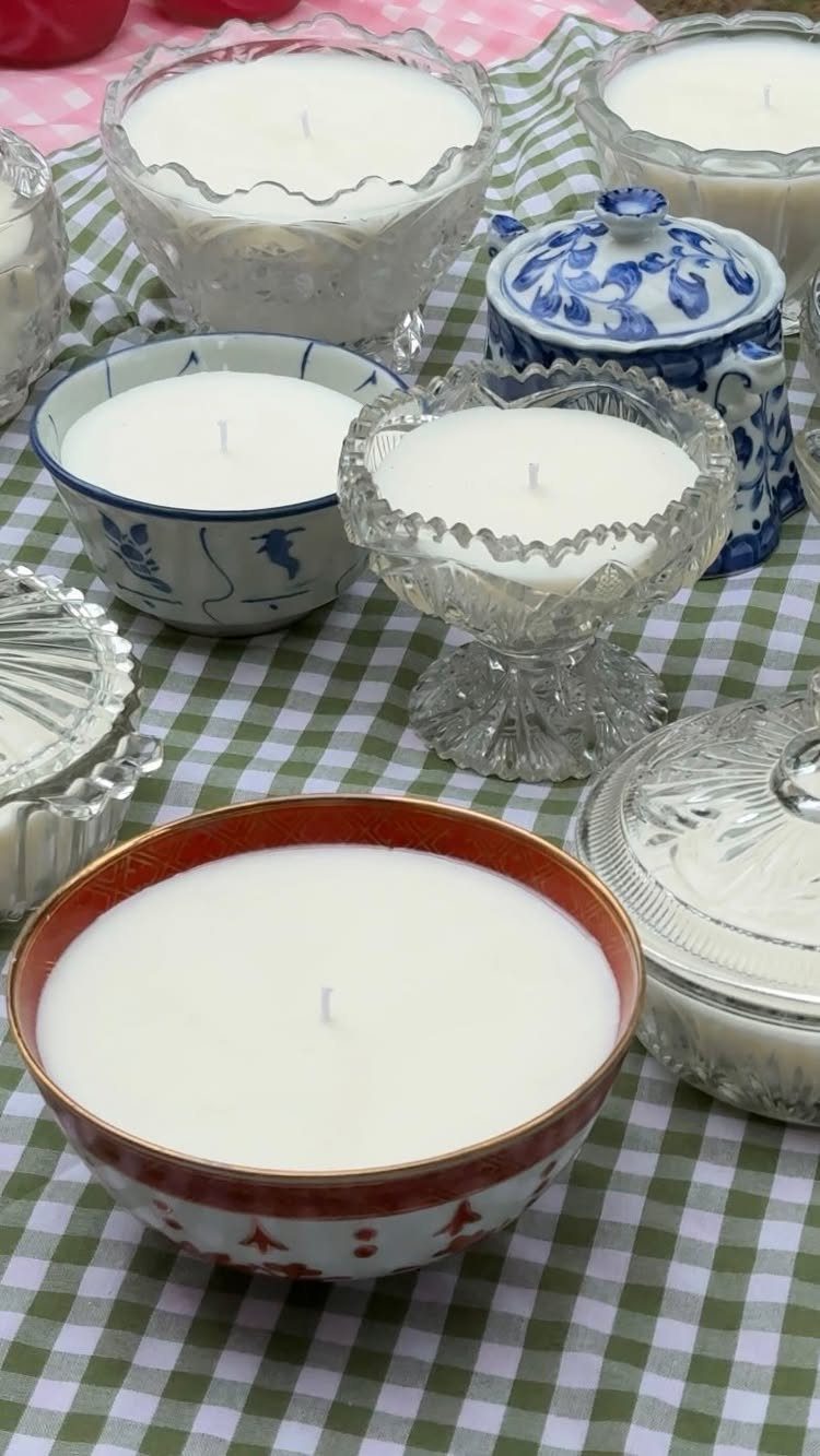 White candles poured into vintage glass and ceramic bowls on checkered tablecloth