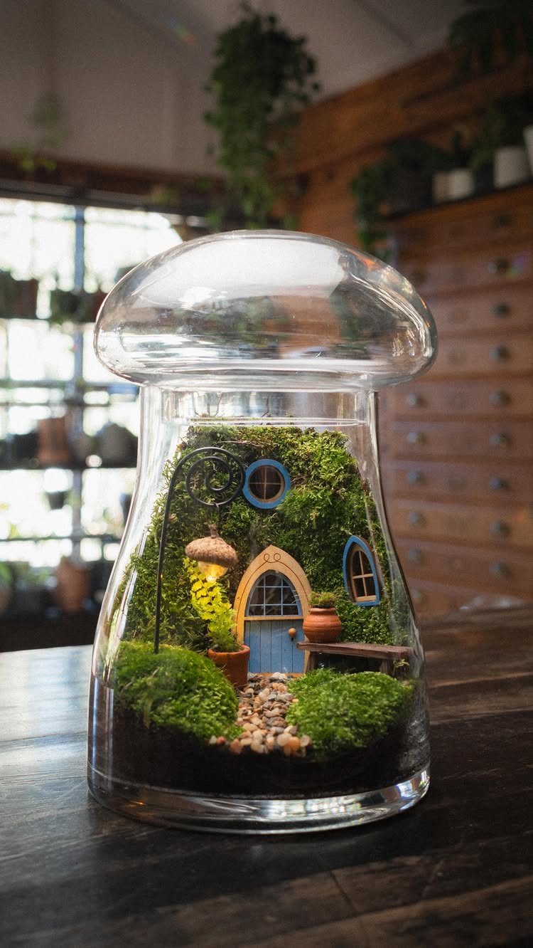 Miniature fairy house with moss and a blue door inside a glass jar.