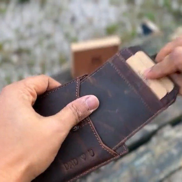 9 Homemade Father's Day Gifts Dad Will Actually Use 7 Hands inserting a personalized card into a brown leather wallet embossed with Dad.
