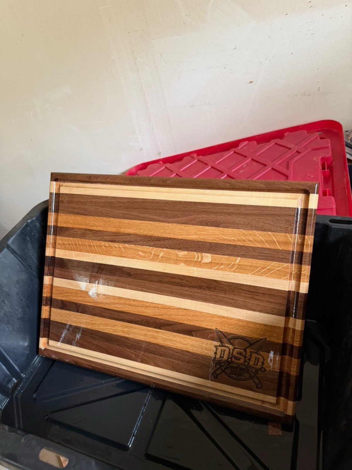 9 Homemade Father's Day Gifts Dad Will Actually Use 4 Striped wooden cutting board with a burned logo leaning against plastic bins.