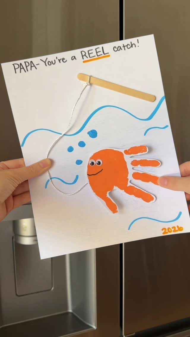 Handmade fishing card with orange handprint fish and a wooden stick fishing pole.