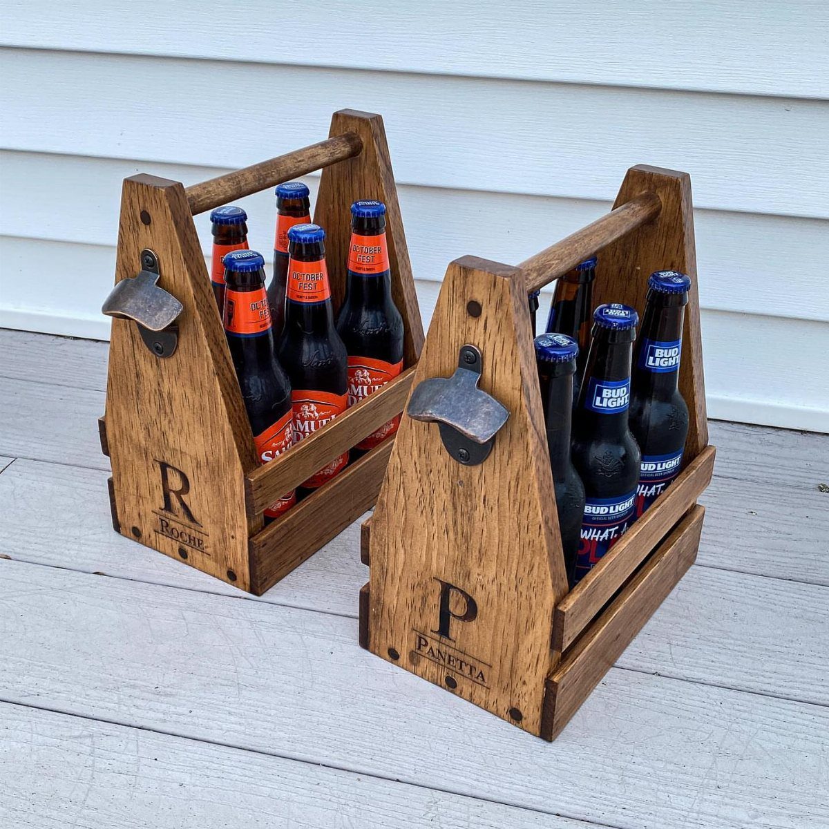 Two personalized wooden beer caddies holding bottles on a light grey wooden deck.
