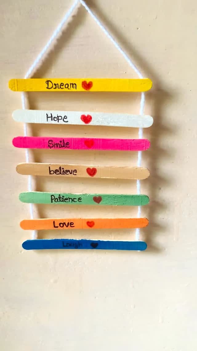 Colorful painted popsicle sticks with inspirational words and red hearts hanging on string.