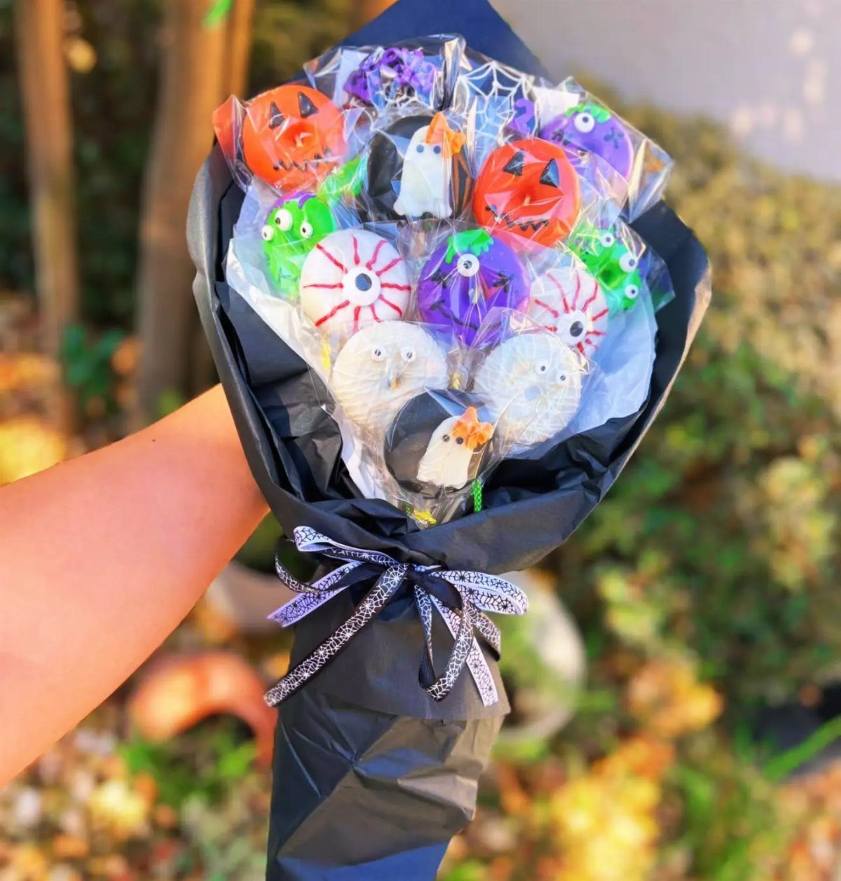 Halloween cake pop bouquet with pumpkins and ghosts wrapped in black paper.