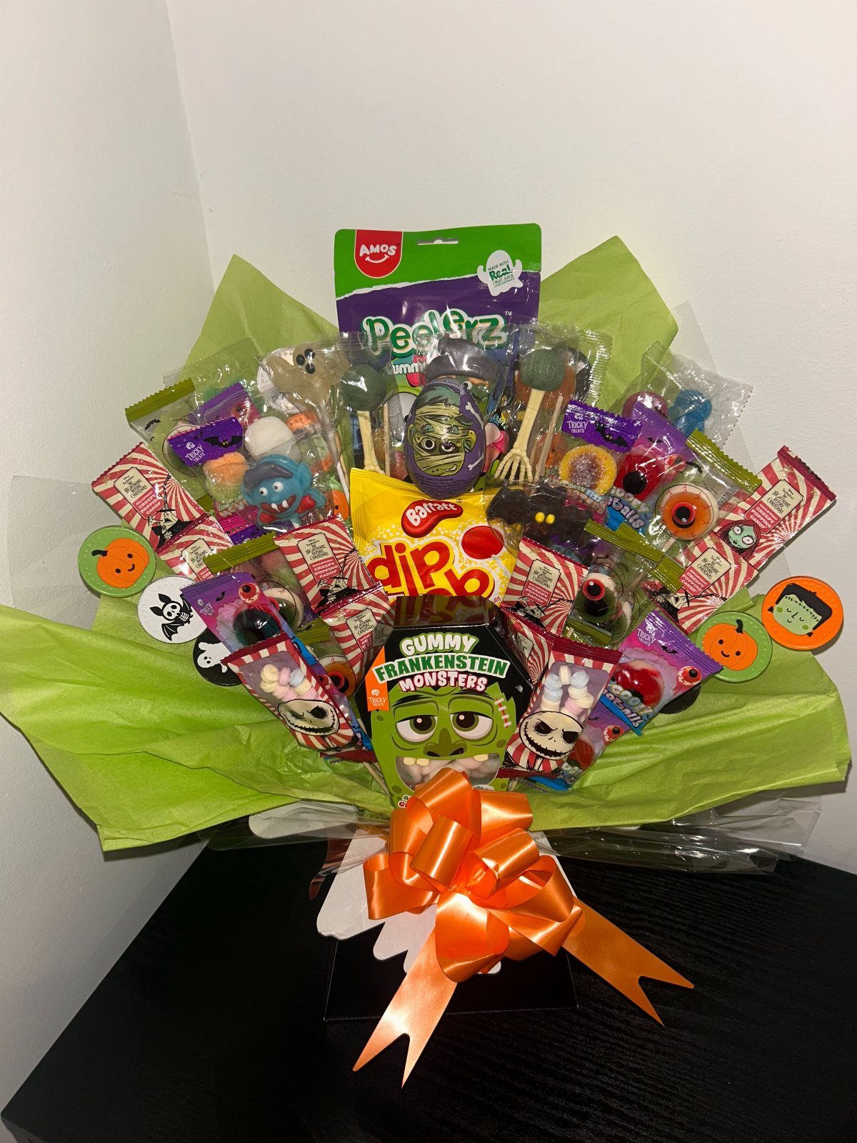 Halloween candy bouquet with green wrapping, orange bow, and assorted spooky sweets.