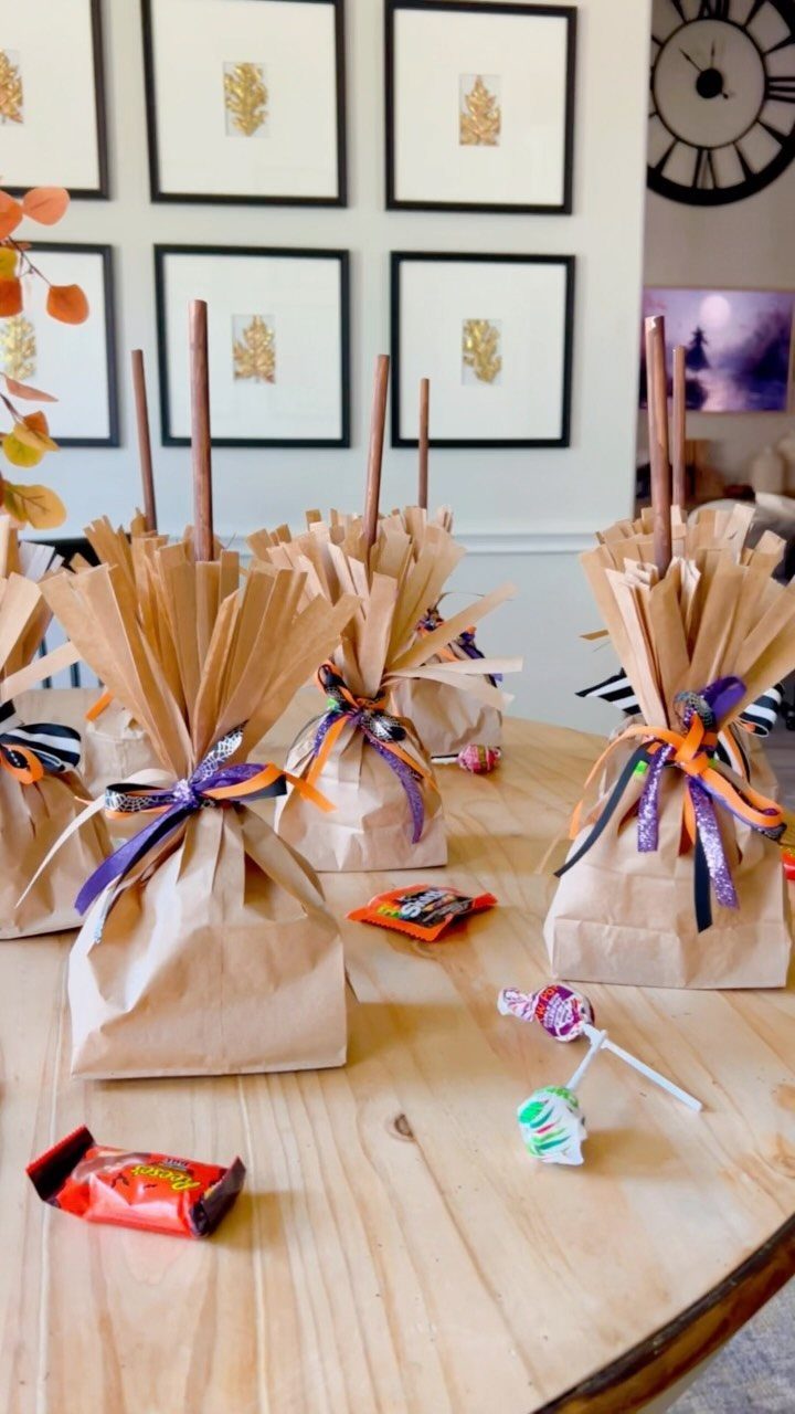 Brown paper gift bags tied with orange and purple ribbons containing pretzel rods.