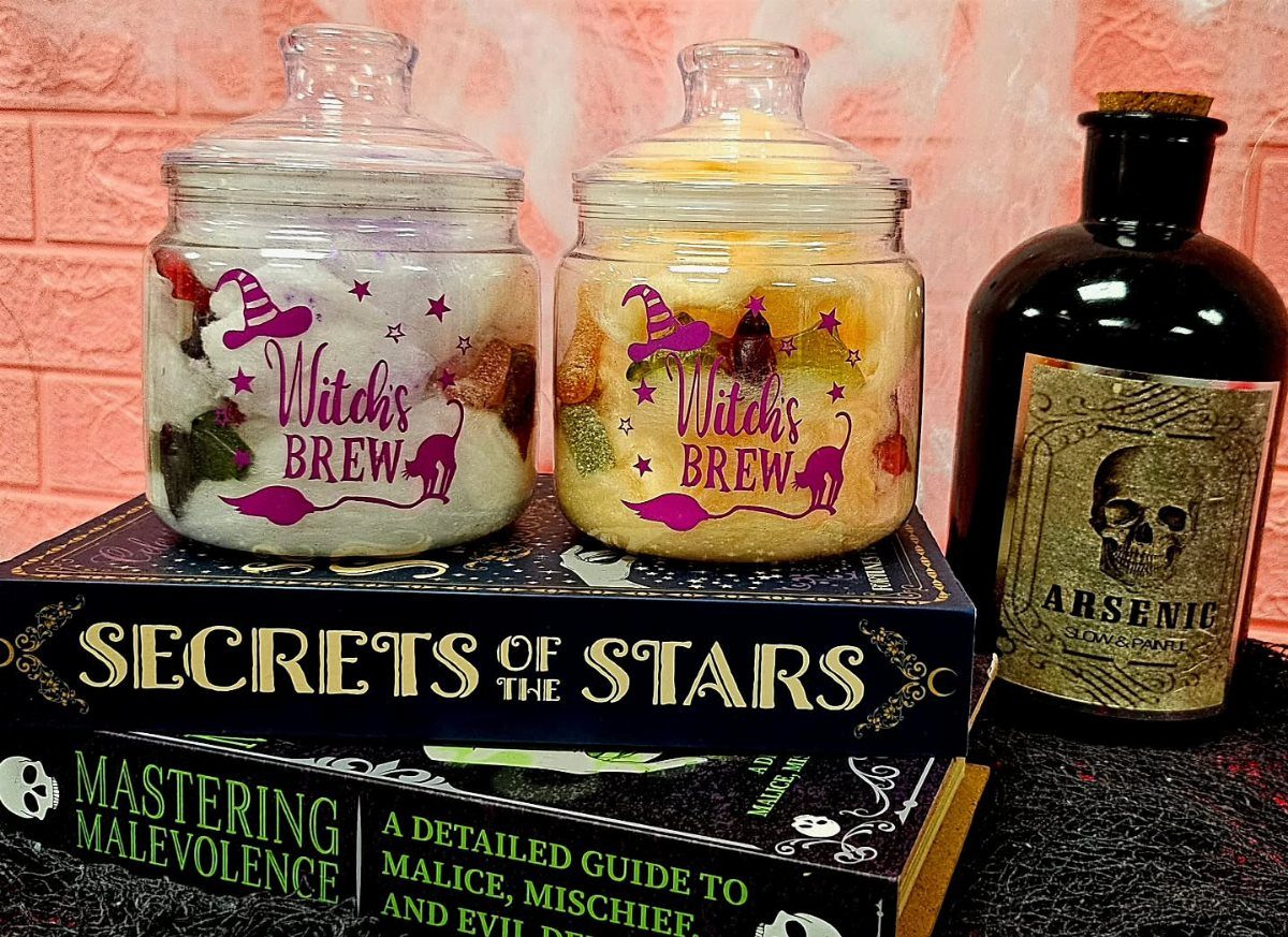 Two Halloween treat jars labeled Witch's Brew sitting on spooky books and a bottle.
