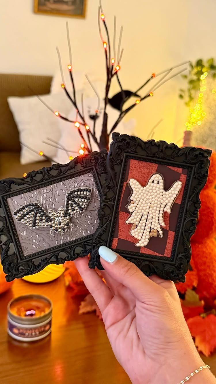 Two small ornate black frames featuring a bat and a ghost design.