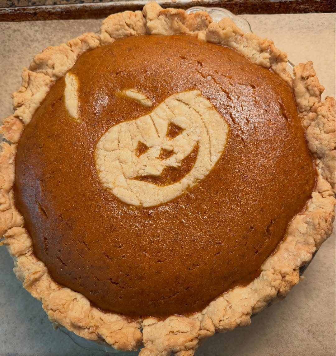 Pumpkin pie with a jack-o'-lantern face made of crust on top.