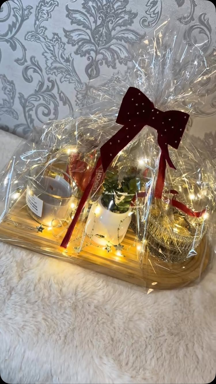 14 Household Gift Basket Ideas for Every Occasion 14 Gift set on wooden tray with candle, plant, and ornament wrapped in cellophane.