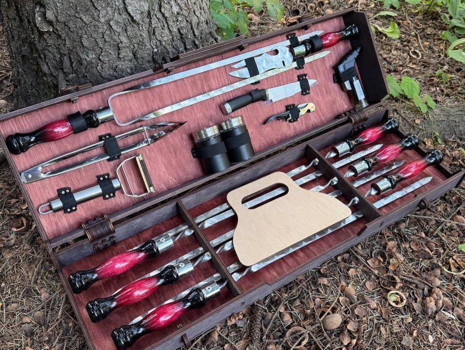 Hunting Gift Basket Ideas: 7 Options to Give This Year 6 Open tool case with red-handled knives and binoculars on a forest floor