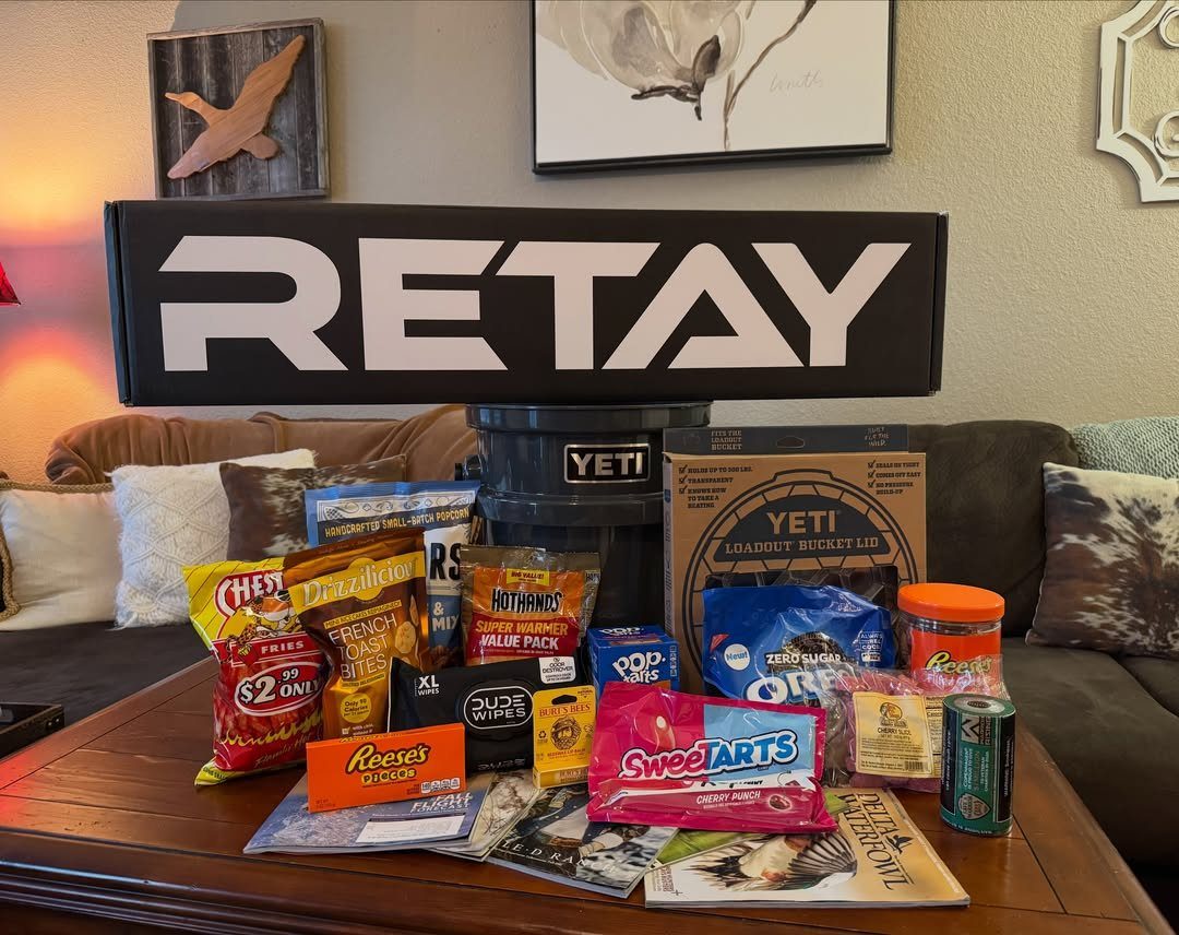 Hunting Gift Basket Ideas: 7 Options to Give This Year 7 Assorted snacks and Yeti gear arranged as a gift on a wooden table.