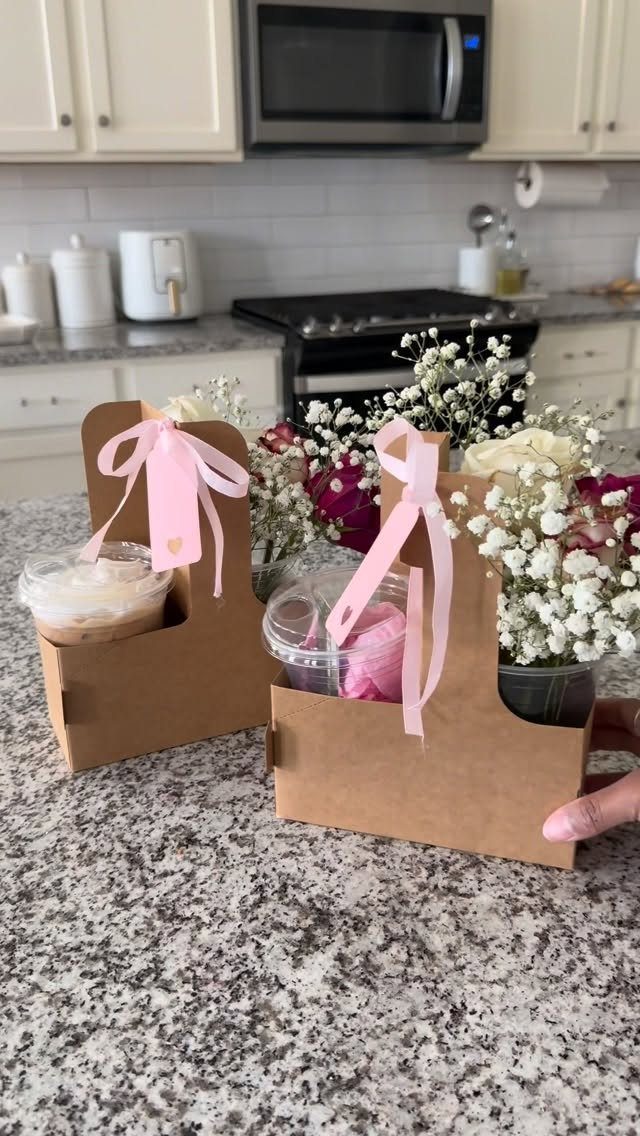 Brown cardboard coffee cup carriers with pink ribbons and drinks on a kitchen counter