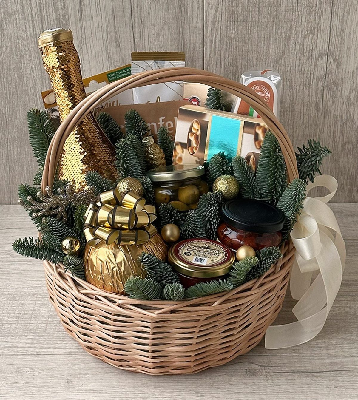 Luxury Gift Basket Ideas: 5 Options for Every Taste 2 Woven gift basket filled with gourmet foods, gold bottle, and pine branches.
