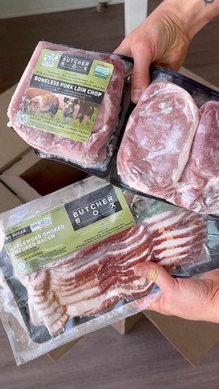 Vacuum-sealed packages of pork chops and bacon held over a shipping box.
