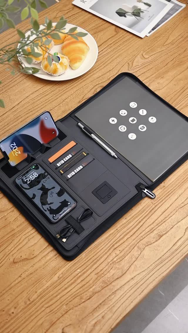 Black leather tech organizer with tablet and phones on a wooden desk