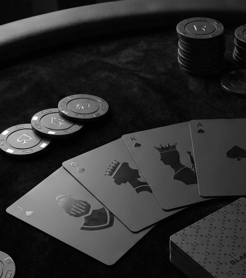 Black playing cards and poker chips arranged on a dark textured surface