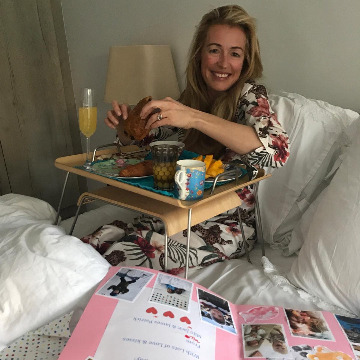 Smiling woman in bed with a breakfast tray and a handmade photo album