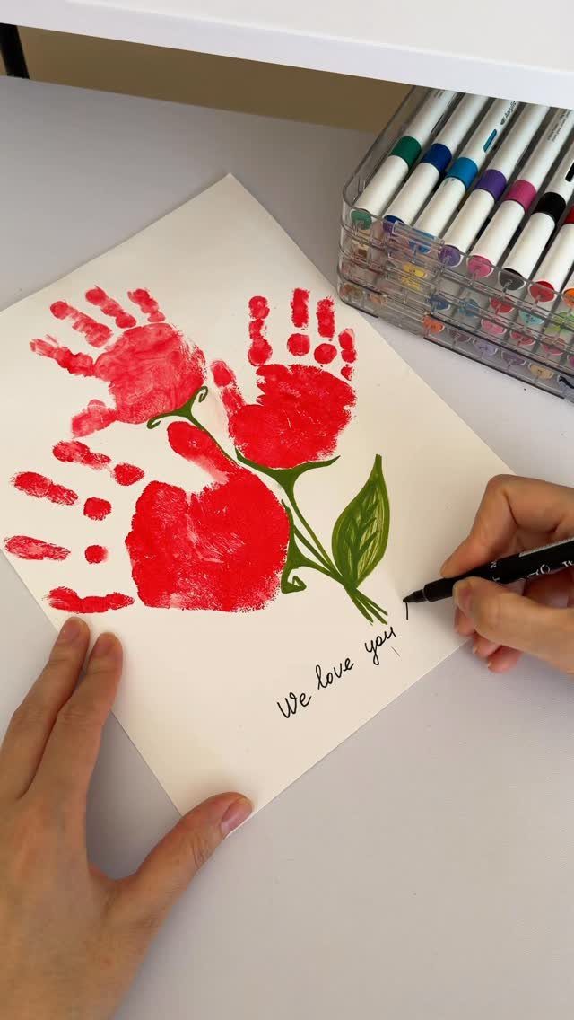 Red handprint flowers on white paper with the words We love you written below.