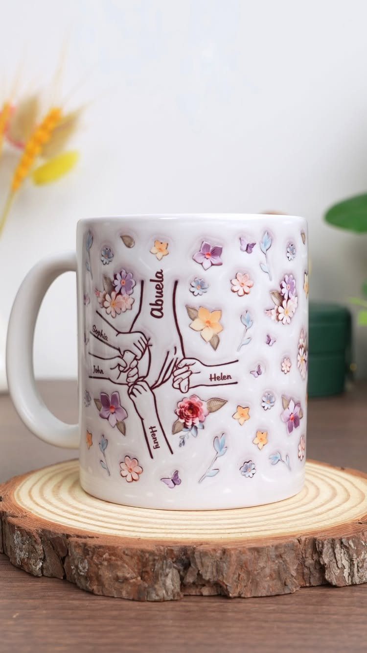 White ceramic mug with floral illustrations and names on a wooden coaster.