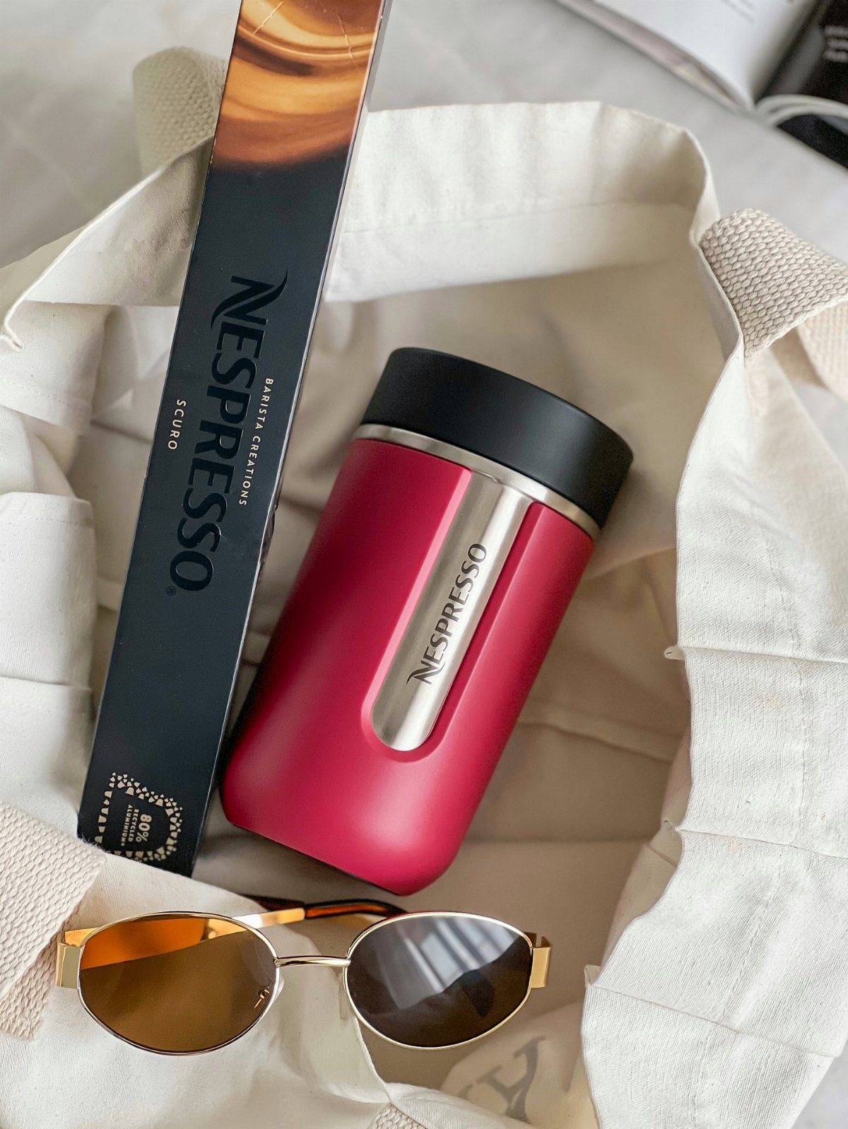 Nespresso Gift Basket Ideas: 5 Ways to Build One 4 Nespresso travel mug and coffee capsules inside a white canvas tote bag with sunglasses