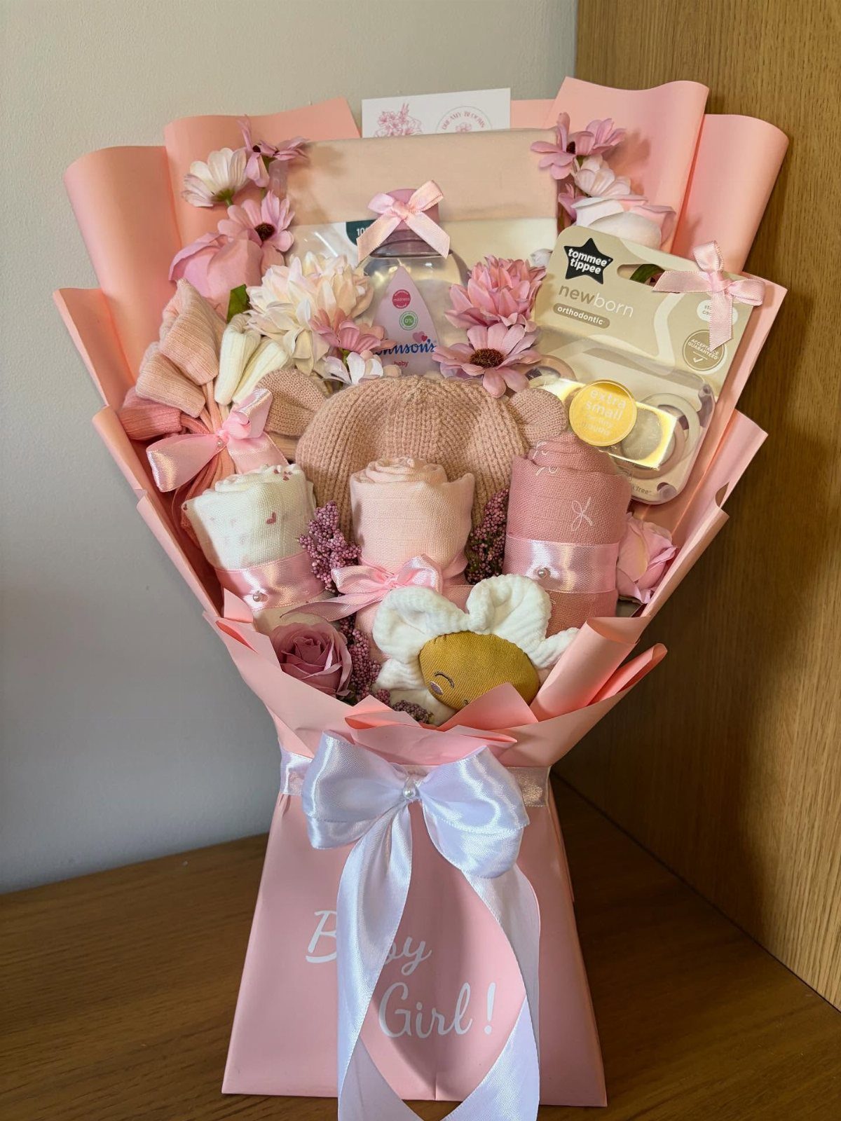 Postpartum Gift Basket Ideas for New Moms: 9 Picks 2 Baby gift bouquet with pink clothes, knit hat, and flowers in pink wrapping.