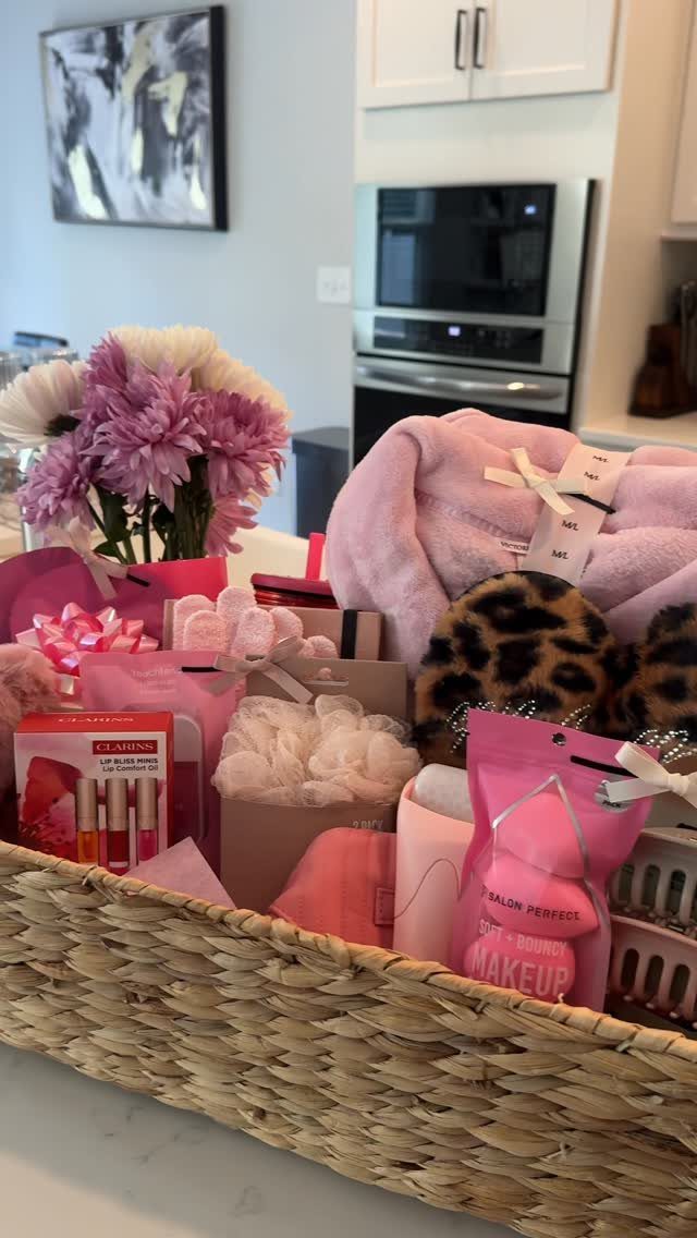 Postpartum Gift Basket Ideas for New Moms: 9 Picks 7 Woven gift basket filled with pink robe, leopard slippers, skincare, and purple flowers.