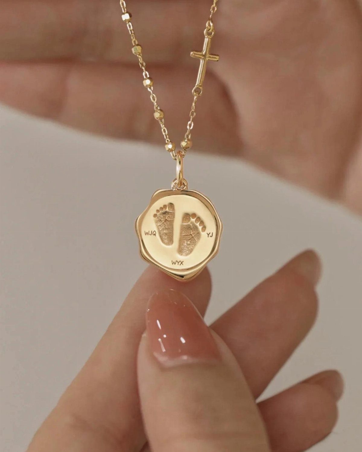 Postpartum Gift Basket Ideas for New Moms: 9 Picks 4 Gold necklace with a pendant engraved with baby footprints and initials held by hand