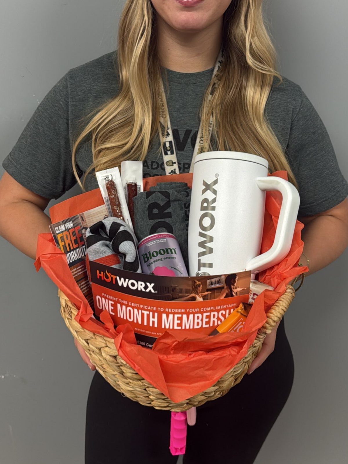 Wicker gift basket with fitness products, a white mug, and a membership voucher.