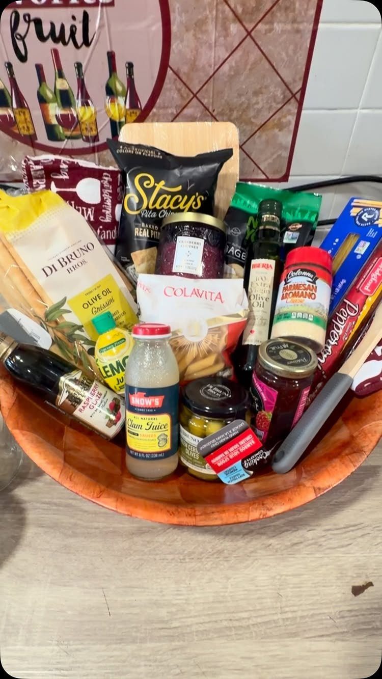Wooden bowl filled with gourmet snacks, pasta, olive oil, and specialty jars.