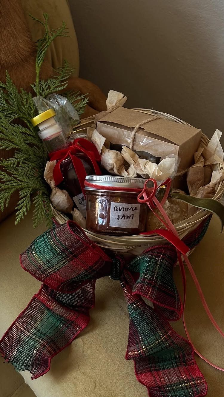 Wicker gift basket with jam jars and a plaid bow for the holidays.