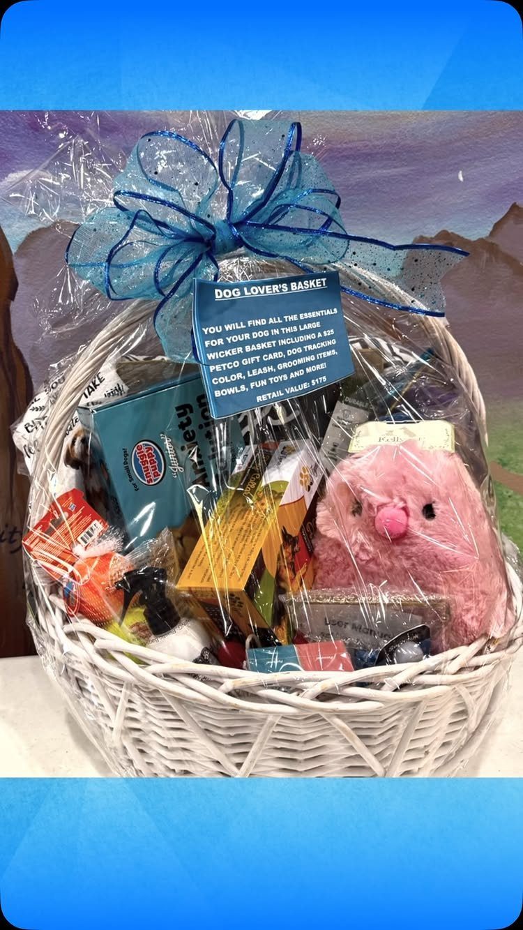 White wicker gift basket filled with pet supplies and a pink plush dog toy.