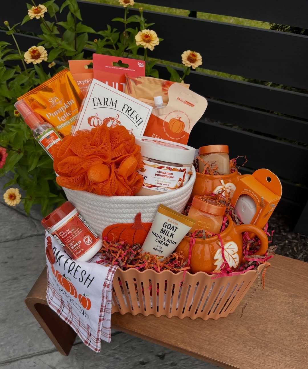 Pumpkin-themed self-care spa gift basket with lotions and creams on a wooden bench.