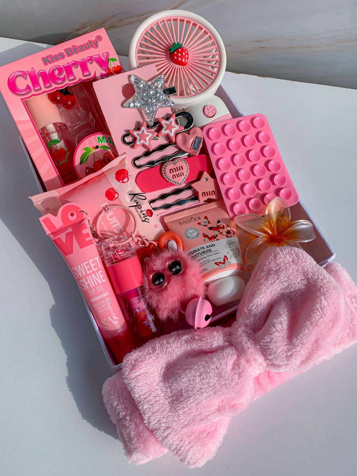Self Care Gift Box Ideas for Any Occasion: 5 Picks 4 Pink self-care gift box containing beauty products, a headband, and a small fan.