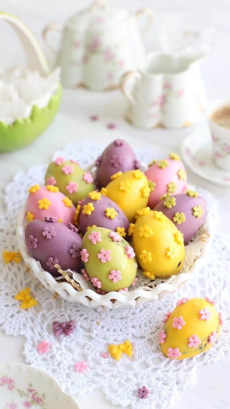Colorful chocolate Easter eggs with flower decorations in a white decorative bowl
