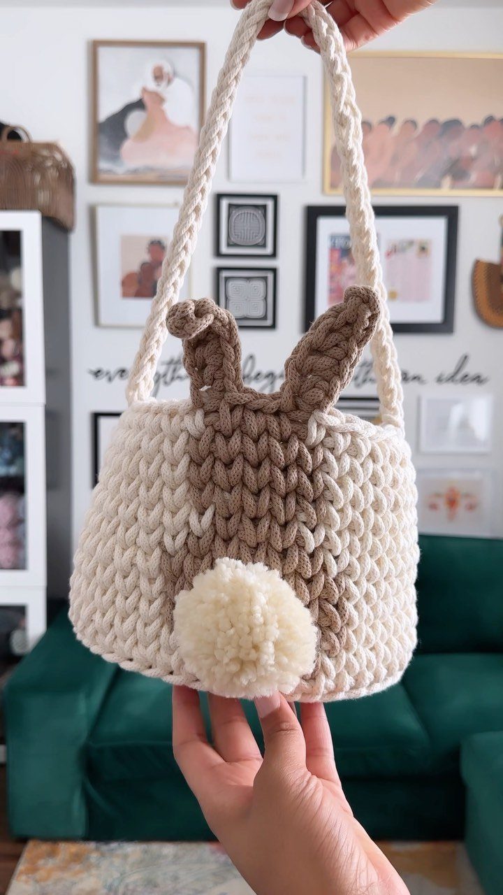Handmade crochet bunny bag in cream and tan held by a person.